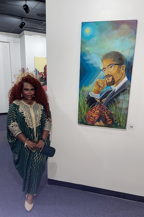 Professor Jessica Kelly standing beside a painting of activist Malcom X