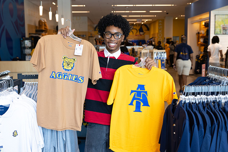 male student holding two shirts
